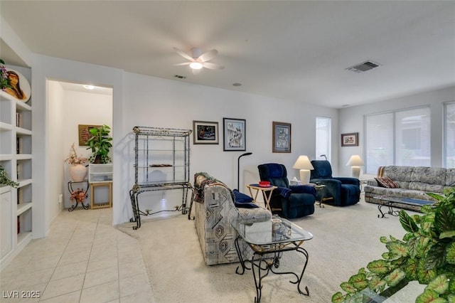 carpeted living room featuring tile patterned floors, visible vents, and a ceiling fan