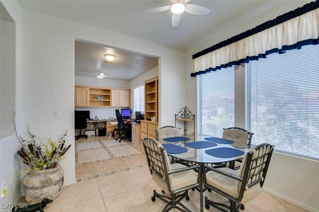 dining space with light tile patterned flooring, ceiling fan, built in study area, and baseboards