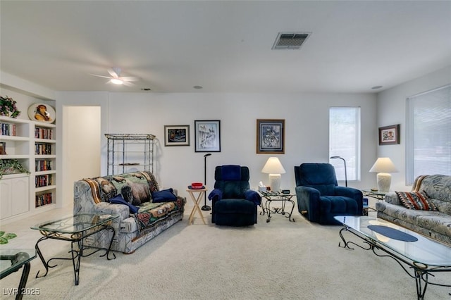 living room featuring visible vents, a ceiling fan, and carpet