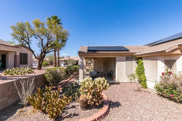 exterior space with a patio area, a tiled roof, stucco siding, and roof mounted solar panels