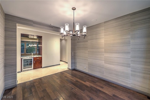 11573 Glowing Sunset Ln, Las Vegas, NV 89135 - unfurnished dining area with beverage cooler, a chandelier, light wood finished floors, bar with sink, and baseboards