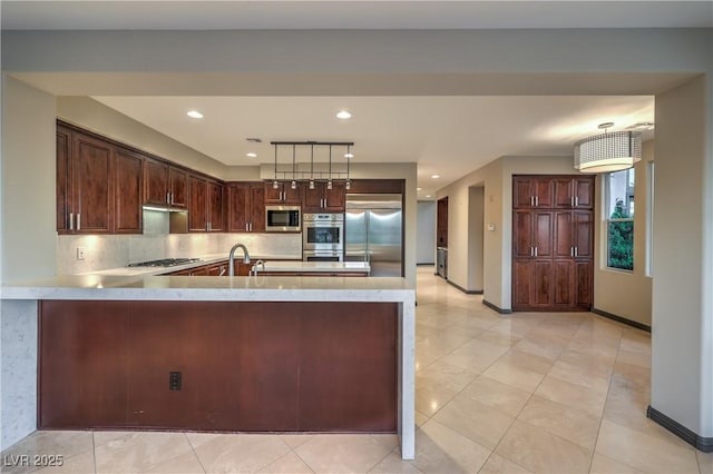 11573 Glowing Sunset Ln, Las Vegas, NV 89135 - kitchen with built in appliances, a peninsula, backsplash, dark brown cabinetry, and baseboards