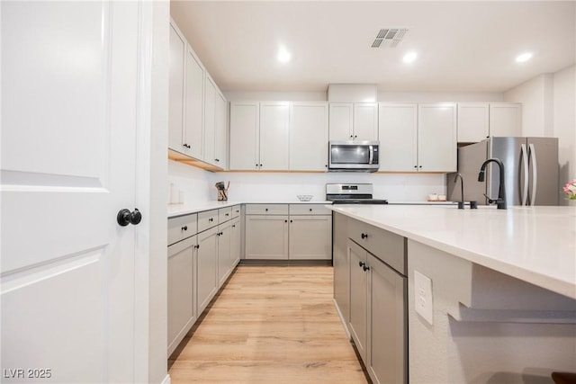3525 Serravalle Ln, Henderson, NV 89044 - kitchen with appliances with stainless steel finishes, light wood-style floors, light countertops, gray cabinets, and recessed lighting