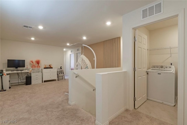 hall with an upstairs landing, washer / dryer, light colored carpet, and visible vents