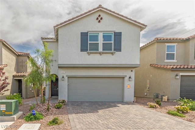 mediterranean / spanish house with a garage, stucco siding, decorative driveway, and a tile roof