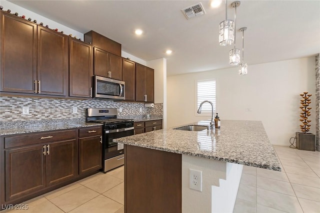 kitchen with light stone counters, backsplash, light tile patterned flooring, stainless steel appliances, and a sink