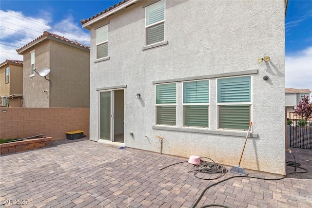 back of house featuring a patio area, a tile roof, fence, and stucco siding
