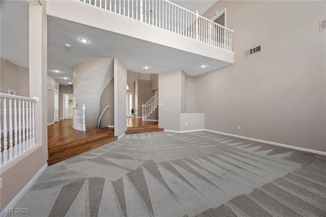 7460 Grassy Field Ct, Las Vegas, NV 89131 - unfurnished living room with carpet flooring, baseboards, stairs, and a towering ceiling