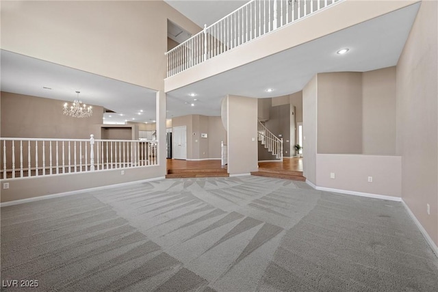7460 Grassy Field Ct, Las Vegas, NV 89131 - unfurnished living room featuring carpet, a high ceiling, baseboards, a chandelier, and stairs