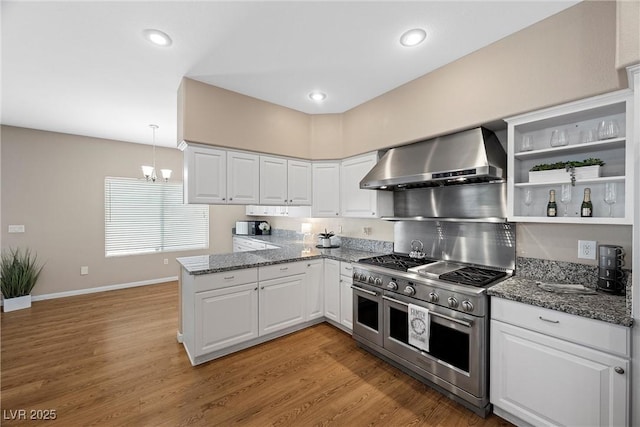7460 Grassy Field Ct, Las Vegas, NV 89131 - kitchen featuring range with two ovens, wall chimney range hood, a peninsula, white cabinets, and recessed lighting
