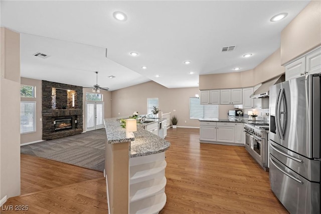 7460 Grassy Field Ct, Las Vegas, NV 89131 - kitchen with appliances with stainless steel finishes, a ceiling fan, open shelves, a fireplace, and baseboards