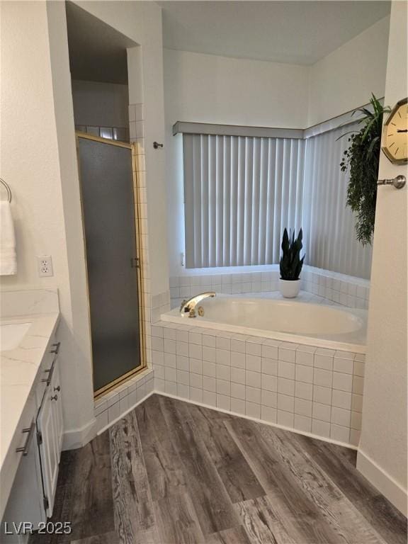 full bath with a shower stall, vanity, a garden tub, and wood finished floors