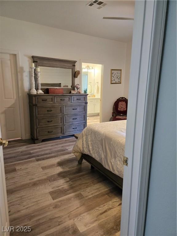 bedroom with visible vents, ensuite bathroom, and dark wood finished floors