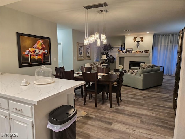 dining room featuring visible vents, wood finished floors, and a fireplace