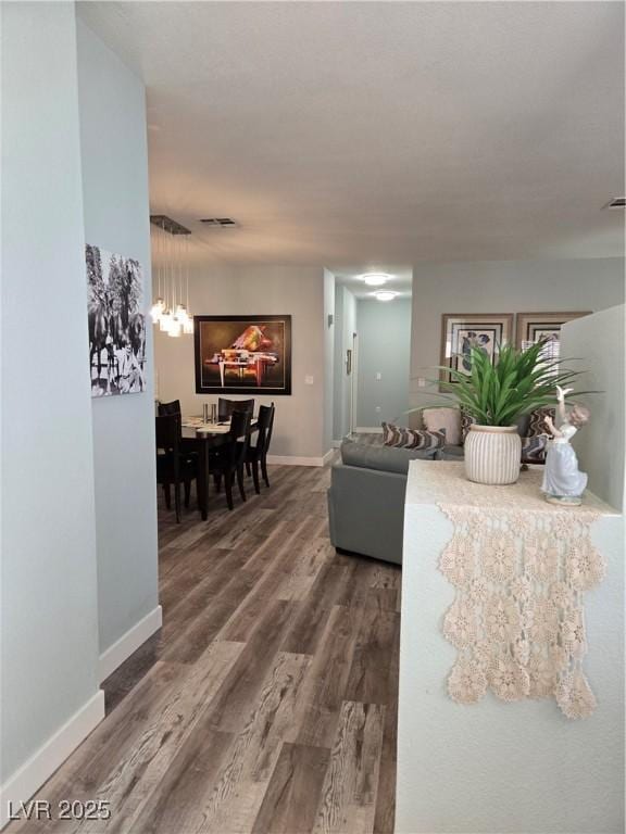 living room with visible vents, baseboards, an inviting chandelier, and wood finished floors