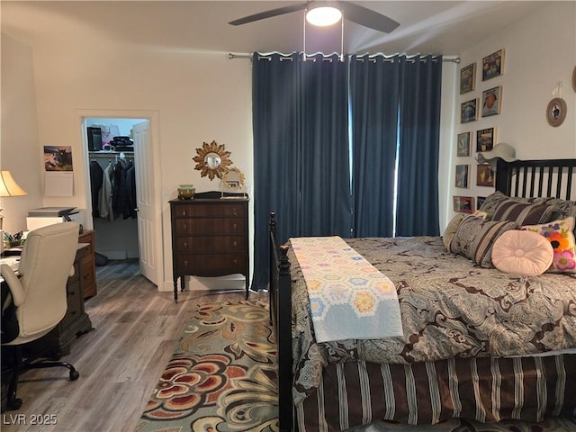 bedroom featuring a closet, ceiling fan, a walk in closet, and wood finished floors
