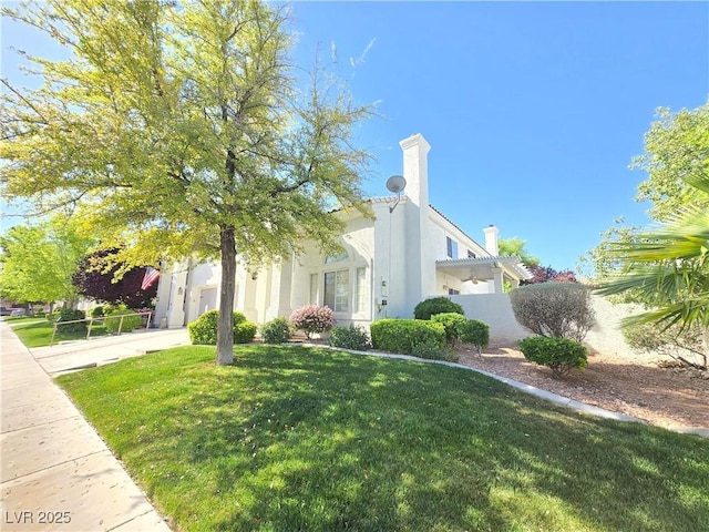view of property exterior featuring a yard, stucco siding, and a chimney