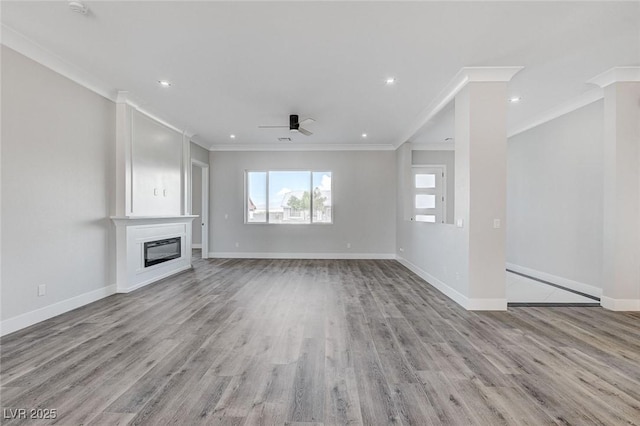 2110 S Manzanita Dr, Pahrump, NV 89048 - unfurnished living room with baseboards, ornamental molding, ceiling fan, light wood-type flooring, and a glass covered fireplace