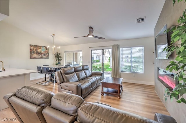 8513 Glenmount Dr, Las Vegas, NV 89134 - living room featuring light wood finished floors, visible vents, baseboards, and ceiling fan with notable chandelier