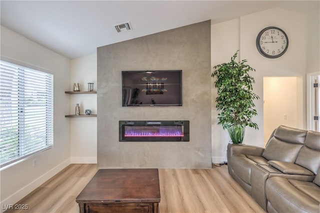 8513 Glenmount Dr, Las Vegas, NV 89134 - living room with wood finished floors, a glass covered fireplace, visible vents, and a healthy amount of sunlight