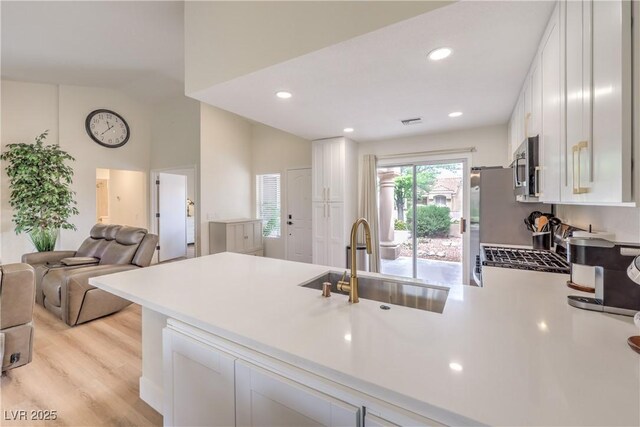 8513 Glenmount Dr, Las Vegas, NV 89134 - kitchen with stainless steel microwave, a peninsula, white cabinets, visible vents, and a sink