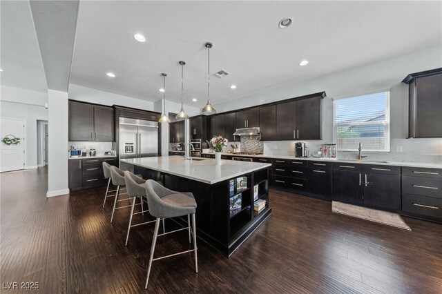 12665 Cooks Bay Ct, Las Vegas, NV 89141 - kitchen featuring built in refrigerator, under cabinet range hood, a center island with sink, a breakfast bar area, and a sink