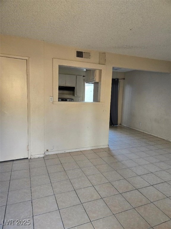 spare room with a textured ceiling, baseboards, and visible vents