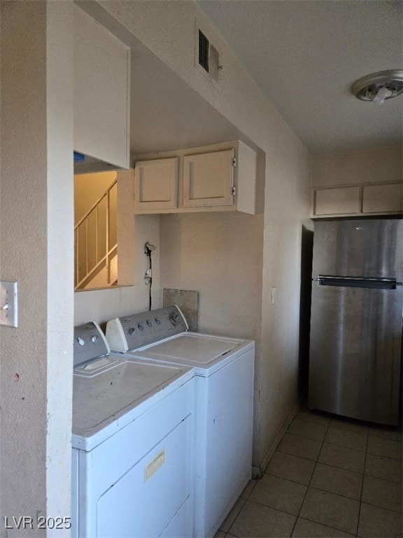 clothes washing area featuring washing machine and dryer, visible vents, and light tile patterned flooring