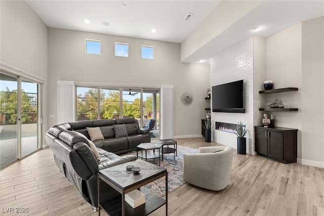 living room featuring light wood-type flooring, a high ceiling, and a healthy amount of sunlight