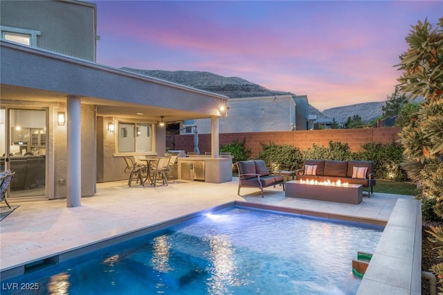 view of swimming pool with a fenced in pool, an outdoor living space with a fire pit, a patio, and a mountain view