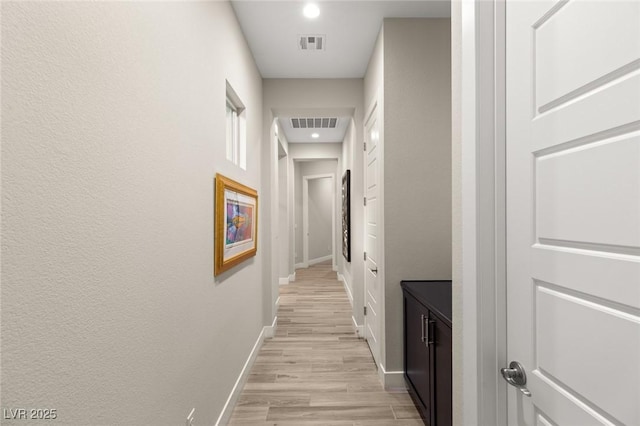 hallway with baseboards, light wood-style floors, visible vents, and recessed lighting