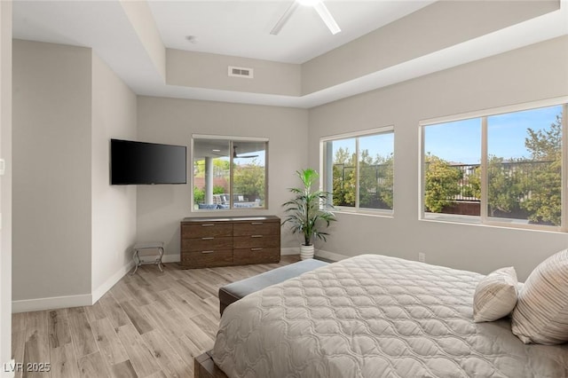 bedroom with light wood-style floors, visible vents, baseboards, and a ceiling fan