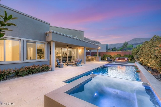 view of pool with a mountain view, outdoor lounge area, fence, a patio, and an in ground hot tub