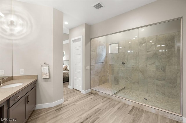 bathroom with vanity, baseboards, wood finished floors, a shower stall, and ensuite bath