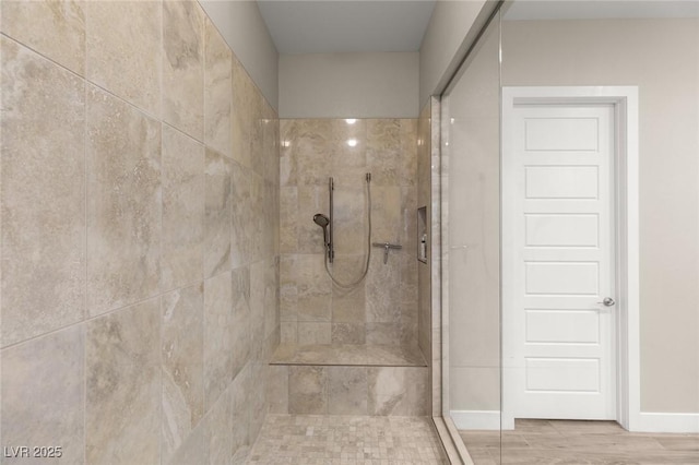 full bathroom featuring a tile shower and baseboards