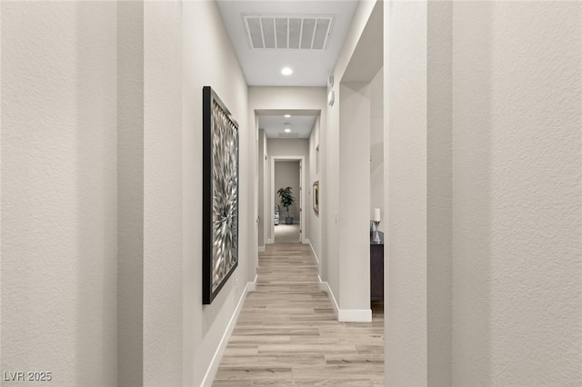 hall featuring light wood-style flooring, baseboards, visible vents, and recessed lighting