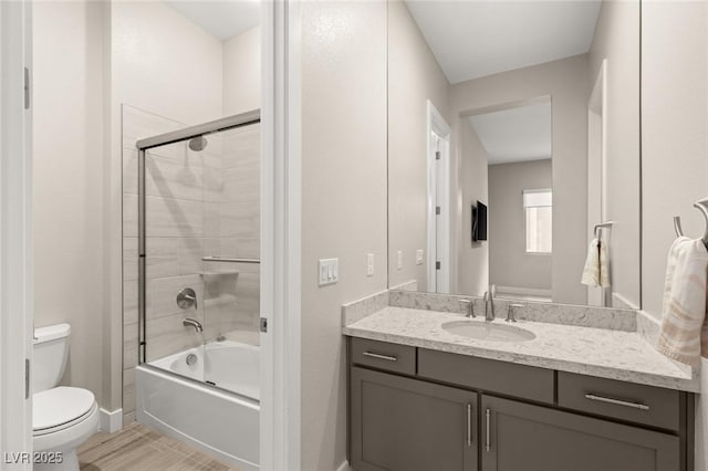 full bathroom with wood finished floors, combined bath / shower with glass door, toilet, vanity, and baseboards