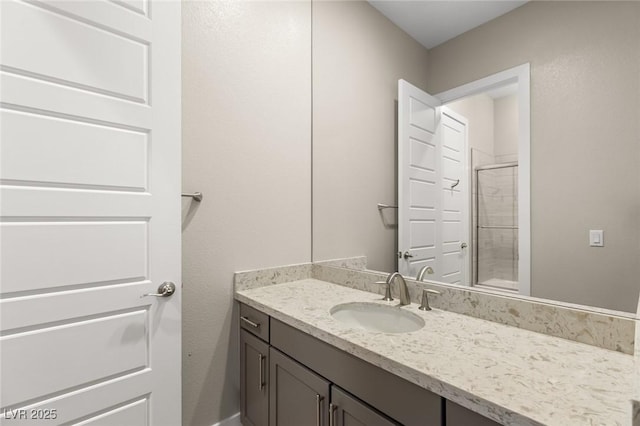 bathroom featuring a shower with door and vanity
