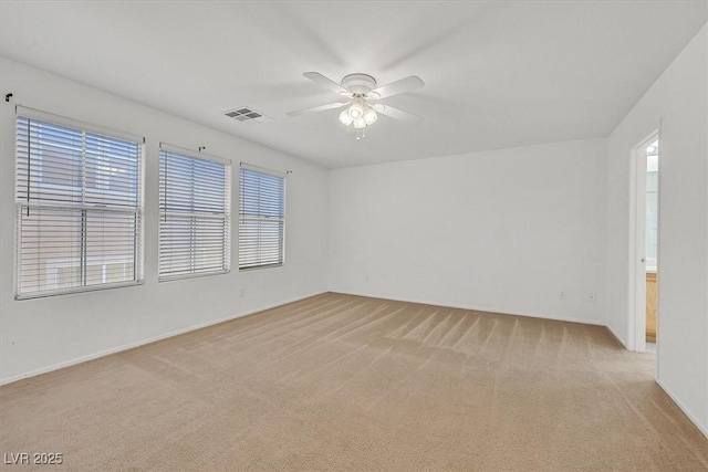 unfurnished room with light colored carpet, a ceiling fan, and baseboards