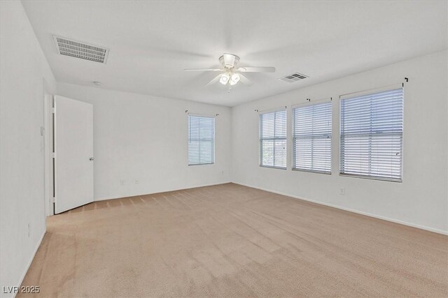 spare room featuring a ceiling fan, light colored carpet, and baseboards
