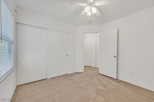 unfurnished bedroom featuring carpet flooring, a closet, baseboards, and a ceiling fan
