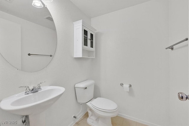 half bathroom featuring toilet, a sink, baseboards, and tile patterned floors
