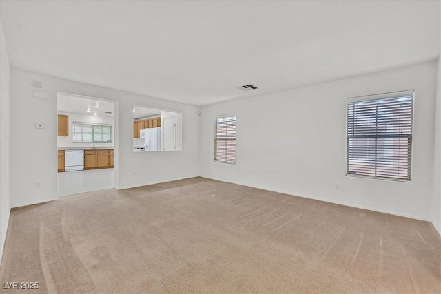 unfurnished living room featuring light carpet and a sink