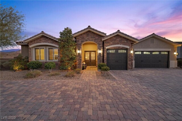 421 Foxhall Rd, Henderson, NV 89002 - view of front of house with stucco siding, stone siding, decorative driveway, a garage, and a tiled roof