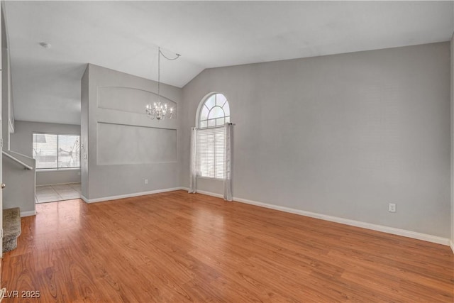 unfurnished room featuring baseboards, a notable chandelier, wood finished floors, and lofted ceiling
