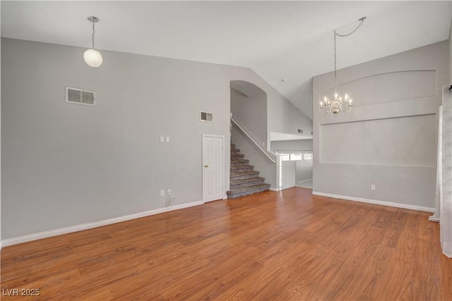 unfurnished living room with high vaulted ceiling, wood finished floors, visible vents, and stairs