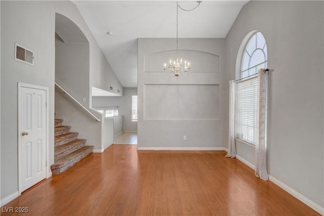 foyer featuring stairs, wood finished floors, visible vents, and a notable chandelier
