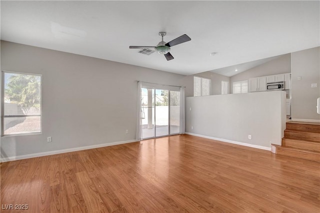 unfurnished living room featuring stairway, a ceiling fan, light wood-style flooring, lofted ceiling, and visible vents