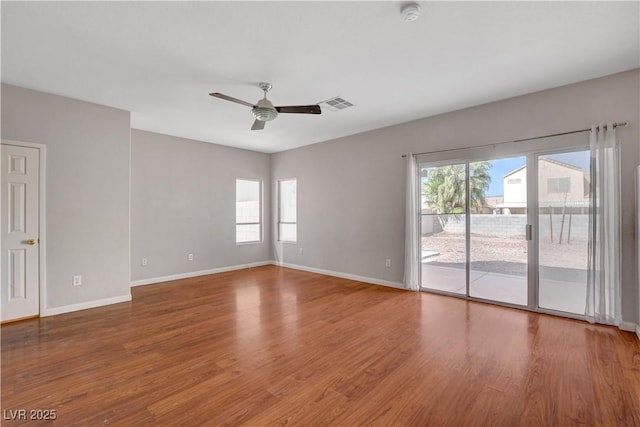 empty room featuring ceiling fan, wood finished floors, and plenty of natural light