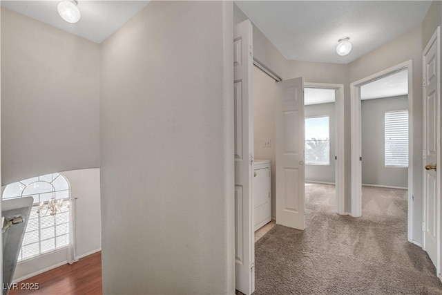 hallway featuring washer / dryer, carpet floors, and baseboards
